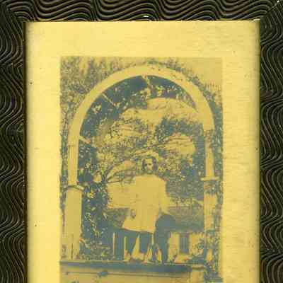 Photograph of a young girl with a dog under a garden archway