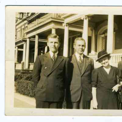 Photograph of 5 people in front of a house