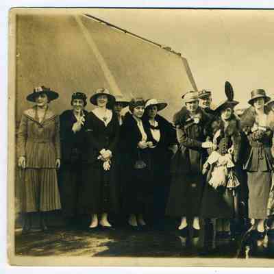 Photograph of a group consisting of 12 women and 2 military men, all wearing hats next to an embankment