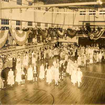 Photograph of people in period costumes in a sports facility