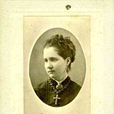 Studio photograph of a young woman with a cross necklace