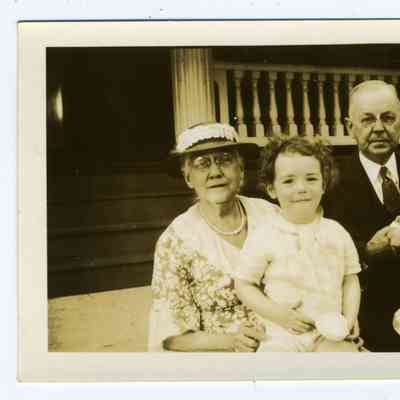 Photograph of an older couple with 3 children sitting on front steps of a house