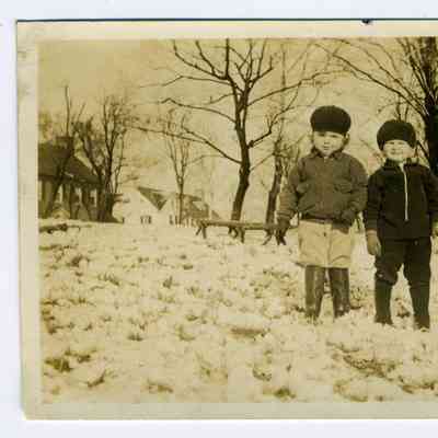 Photograph of two boys with boots standing on snow covered field