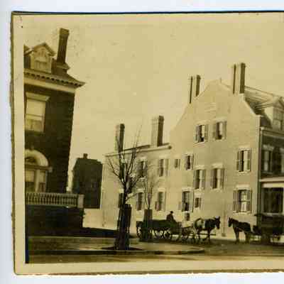 Photograph of horse drawn carriages along a tree lined city street in a residential neighborhood