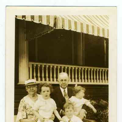 Photograph of an oder couple with three children sitting on steps