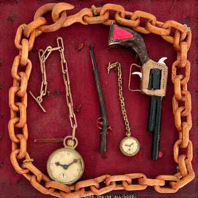 BOARD OF CARVED CHAINS- WATCHES- GUNS