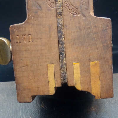Detail of plane front.: Plane clamped over the spacer. Showing the ends of the boxwood wear strips, and the original stamp marks.