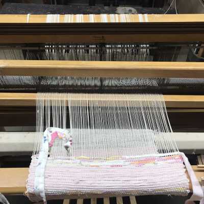 Currently there is a rag weaving on this loom, possibly to make a woven rag rug. Both scrap fabrics are still attached to the main weave with two being still wound about their shuttles.