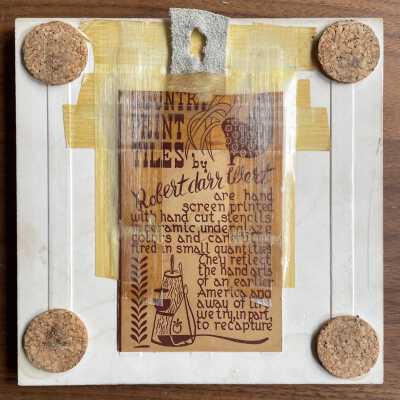 Back of tile with partial Country Print Tiles label hanger and cork pads.