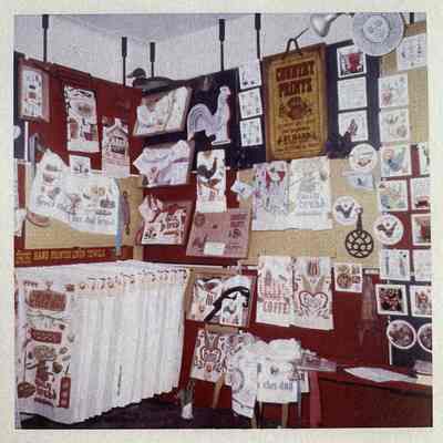 Country Prints product tags stapled to wall hangings/towels, lower left corner of 1960’s Country Prints trade show booth.: Image: Collection of Sara Leeper.