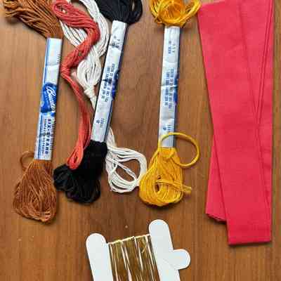 Embroidery floss, mylar thread, and red towel border fabric.