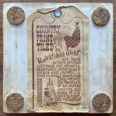 Back of tile with Country Print Tiles label hanger and cork pads.