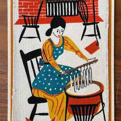 Candlemaking: A woman seated on a spindle back chair dips candles in a vat of wax. Beyond, candles harden on a rod resting on two chair backs. A variation of this design was also produced on a tile. (Six colors)