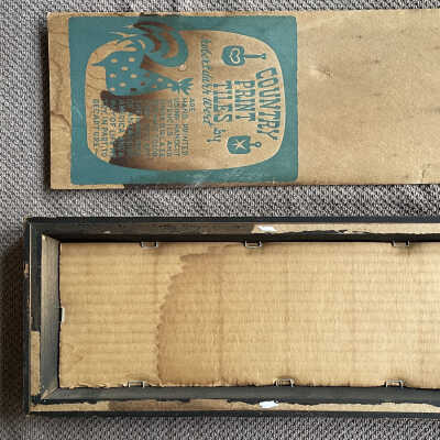 Back of framed tile triptych with backing panel removed.: Tiles are laid in frame, backed with corrugated cardboard, and stapled in place. The printed backing panel is glued into a shallow rabbet making it almost flush with the wood frame.