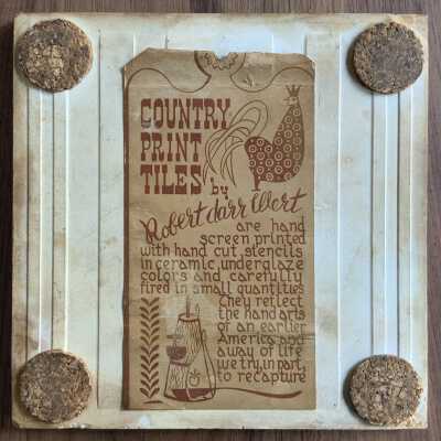Back of tile with Country Print Tiles label hanger and cork pads.