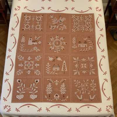 A finished cross stitch quilt by the Bucilla Needlework kit company, American Provincial 2868; see “Kits”.: Produced in black, white and red cross stitch on brown and white cotton fabric. PKM collection.