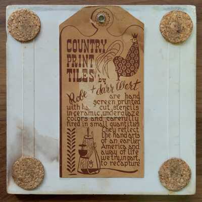 Back of tile with Country Print Tiles label hanger and cork pads.