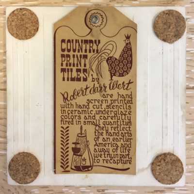 Back of tile with Country Print Tiles label hanger and cork pads.