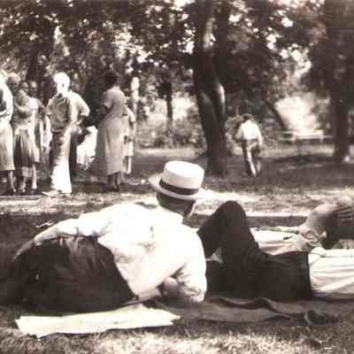 City Park, Hillsboro, ND: Men (Matt Halvorson, Jens Figenskau, and Martin Leet?) relaxing in foreground at picnic reunion. [written on back of photo: "Picnic in the Park, Hillsboro"]