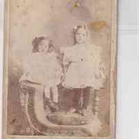 Portrait of Two Young Girls Seated on Wicker Studio Chair with Fur Throw