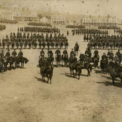 2022.057.004 Recto: Black and white photograph of the 11th Cavalry at Fort Greenleaf's Parade Grounds.