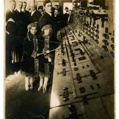 2022.057.074 Recto: Black and white photograph showing spectators at the opening of Halle's Bar Dam standing in front of a control panel