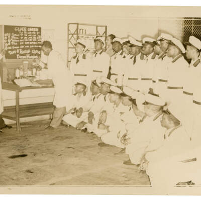 2022.024.015 Recto: Black and white photograph of a body and fender repair class at Boone Higgins Trade School