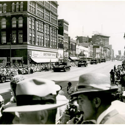 2021.003.002 Parade View From Reviewing Stand: View of the parade, showing a jeep and five tanks carrying armed forces personnel. (photographer Delmont Wilson)