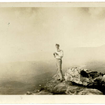 2020.205.002: Man standing on Sunset Rock, holding a camera