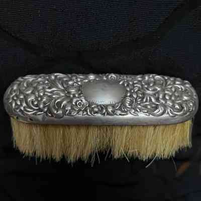 Brush with curved ends and silver grip with floral motif, c. 1900