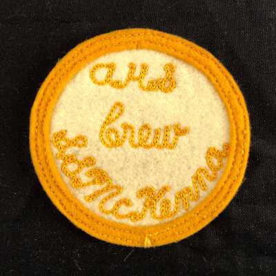 Cicular emblem of Alameda High School of white and gold felt with gold embroidery, c. 1950s