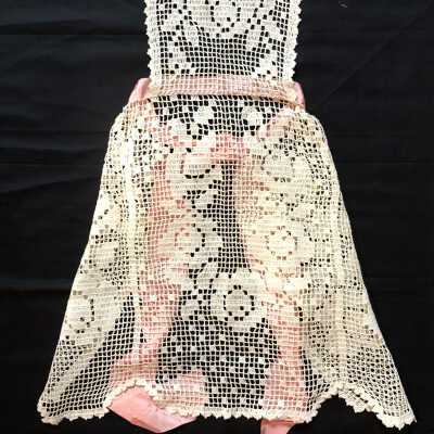 Apron with white hand-crocheted design with floral motif and pink ribbon, before 1998