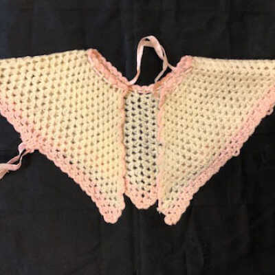 Hand crocheted off-white wool baby cape with pink edging and ribbon, c. 1920s