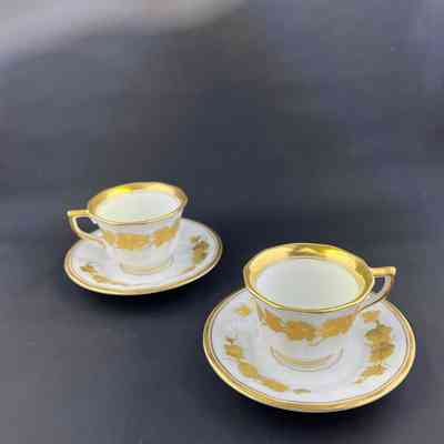Pair of white Royal Copenhagen demitasse cups and saucers with design of gold leaves