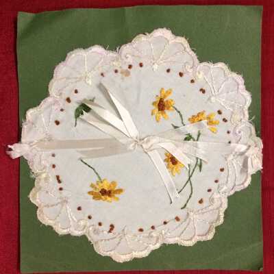Machine-embroidered circular white linen doily with yellow flowers, early 1900s