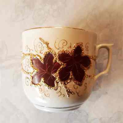 Cream porcelain mustache cup with raised slip work and burgundy leaves, c. 1900