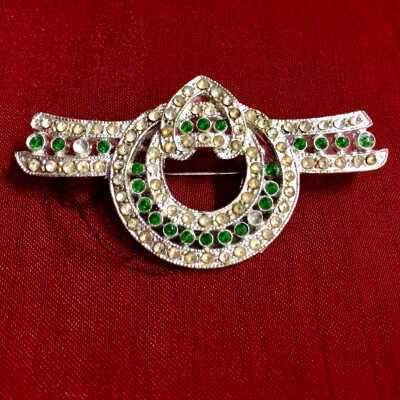 Silver plated brooch of a stylized ribbon with rhinestones and green glass, 1930