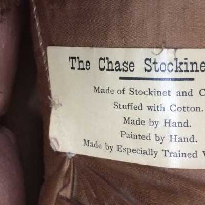 Maker's label: The Chase Stockinet Doll.
Made of Stockinet and Cloth.
Stuffed with Cotton.
Made by Hand.
Painted by Hand. 
Made by Especially Trained Workers.
