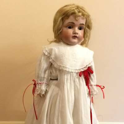 Blonde, brown-eyed German bisque doll dressed in white dress, c. 1900