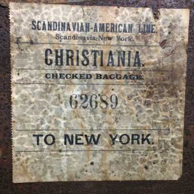 checked baggage shipping label: 
SCANDINAVIAN-AMERICAN LINE
Scandinavia-New York.
CHRISTIANIA.
CHECKED BAGGAGE
    62689
TO NEW YORK

Note: Christiania is now Stockholm