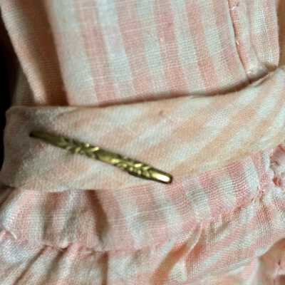 Ribbon: Ribbon of same fabric and pin tied around doll 82.28.27.B (the one without stand)