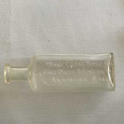 Iridescent medicine bottle advertising White Cross Drug Co., c. early 1900s