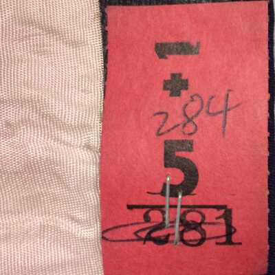 tag stapled to inside brim. Meaning unclear.