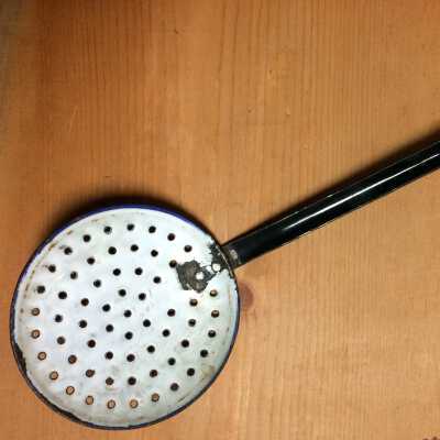Spoon-like black and white enamel strainer of the Macdonald faily, c. 1920s