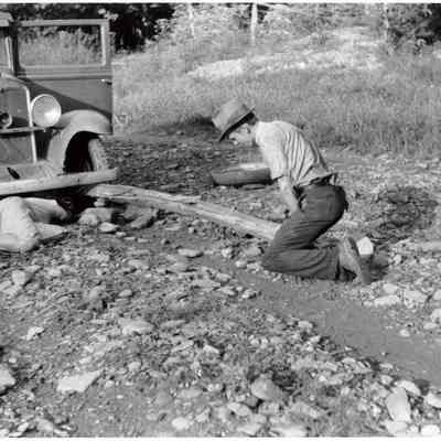 Mountaineer and Marion Post Wolcott changing a tire with a fence post as a jack, up South Fork of the Kentucky River, Kentucky