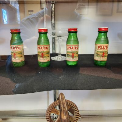 Display case of Averill Family-Owned Items - Close up 2: Pluto Concentrated and Fortified Spring Water bottles from French Lick, Indiana, known as America's Laxative.