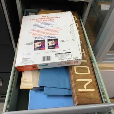 SLHS-FC4 D1: Stores SLHS stationery (envelopes, letterhead, etc.), sheet protectors, and a wooden "Donation" sign, which was apparently used at one time to solicit donations during SLHS events.