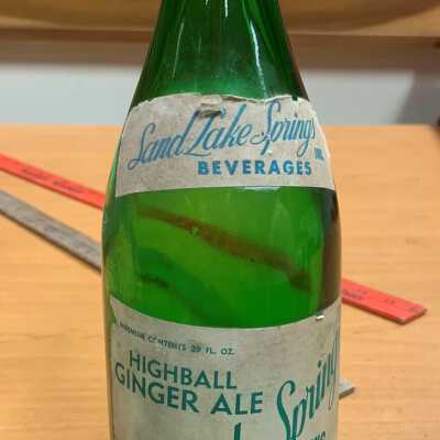 Sand Lake Springs, Highball Ginger Ale, Soda Bottle: JPG photo.  A rare example of a Sand Lake Springs bottle with the original label still attached.  Part of the personal collection of SLHS member and former President Jackie Tremont as of April of 2022.