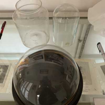 Miscellaneous Glass Items: A blown glass jar with a large pontil mark on the bottom and two glass domes one with a base.  None of which appear to be particularly old or rare, but may be of use for displays.  All three are wrapped and stored in a grey archival box located in Drawer 3 of SLHS File Cabinet 3.