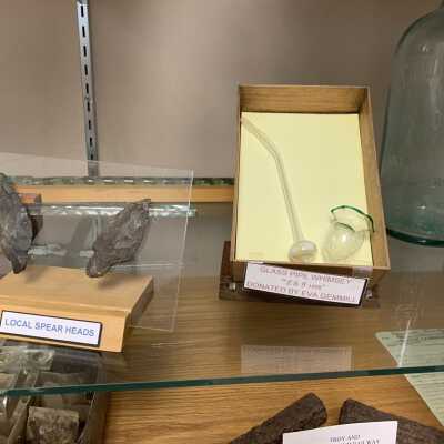 Various Artifacts and Photos Display - Left Side Close Up Bottom Shelves - 4: Various Artifacts and Photos Display - Left Side Close Up Bottom Shelves -4.  Includes glass canes, a glass pipe, Native American Artifacts, egg mailers, and two Troy and New England Railroad Trolley spikes.